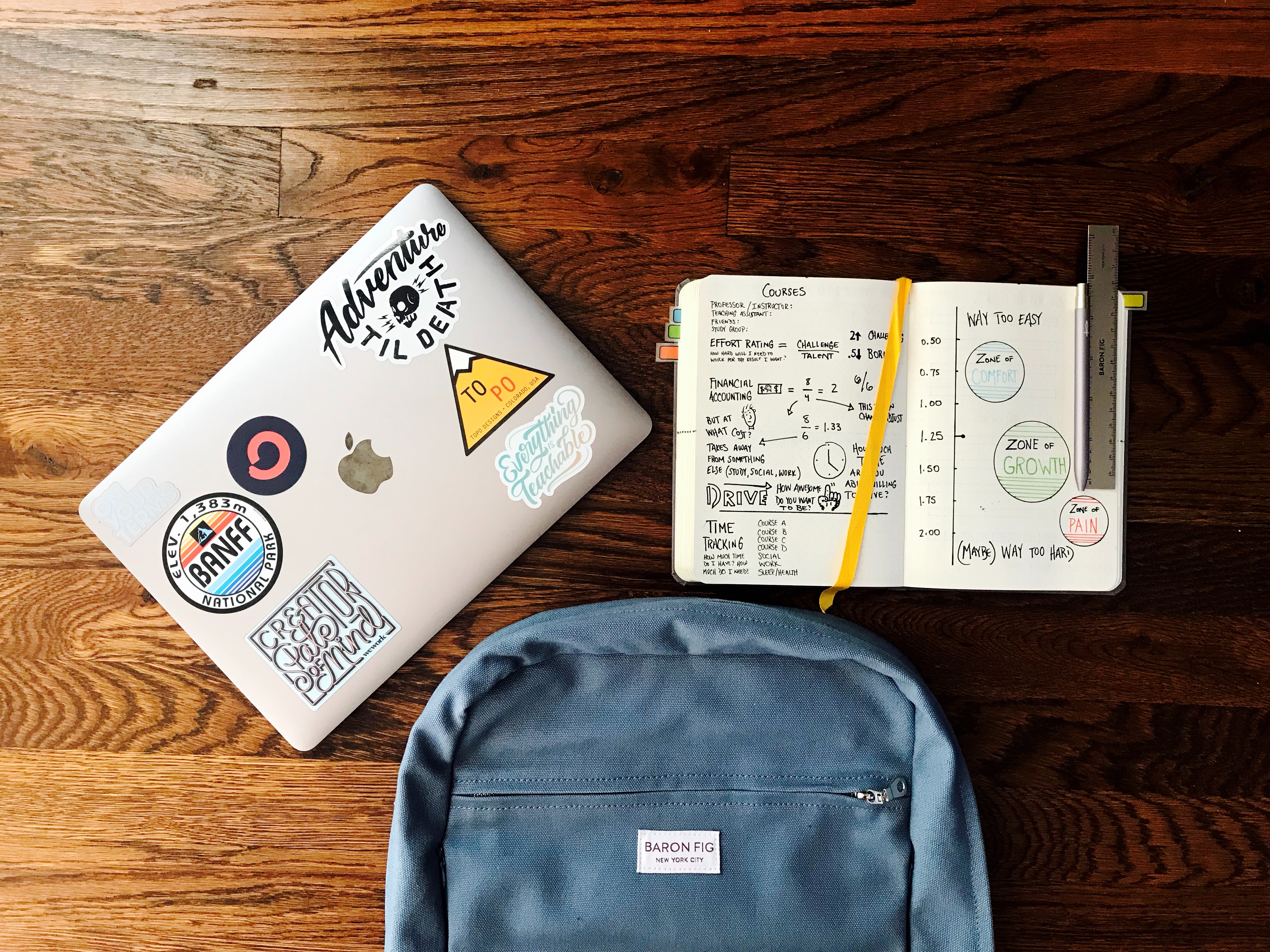 image of a laptop, planner, and backpack on a table